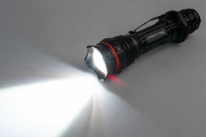 Black flashlight shining light on the ground